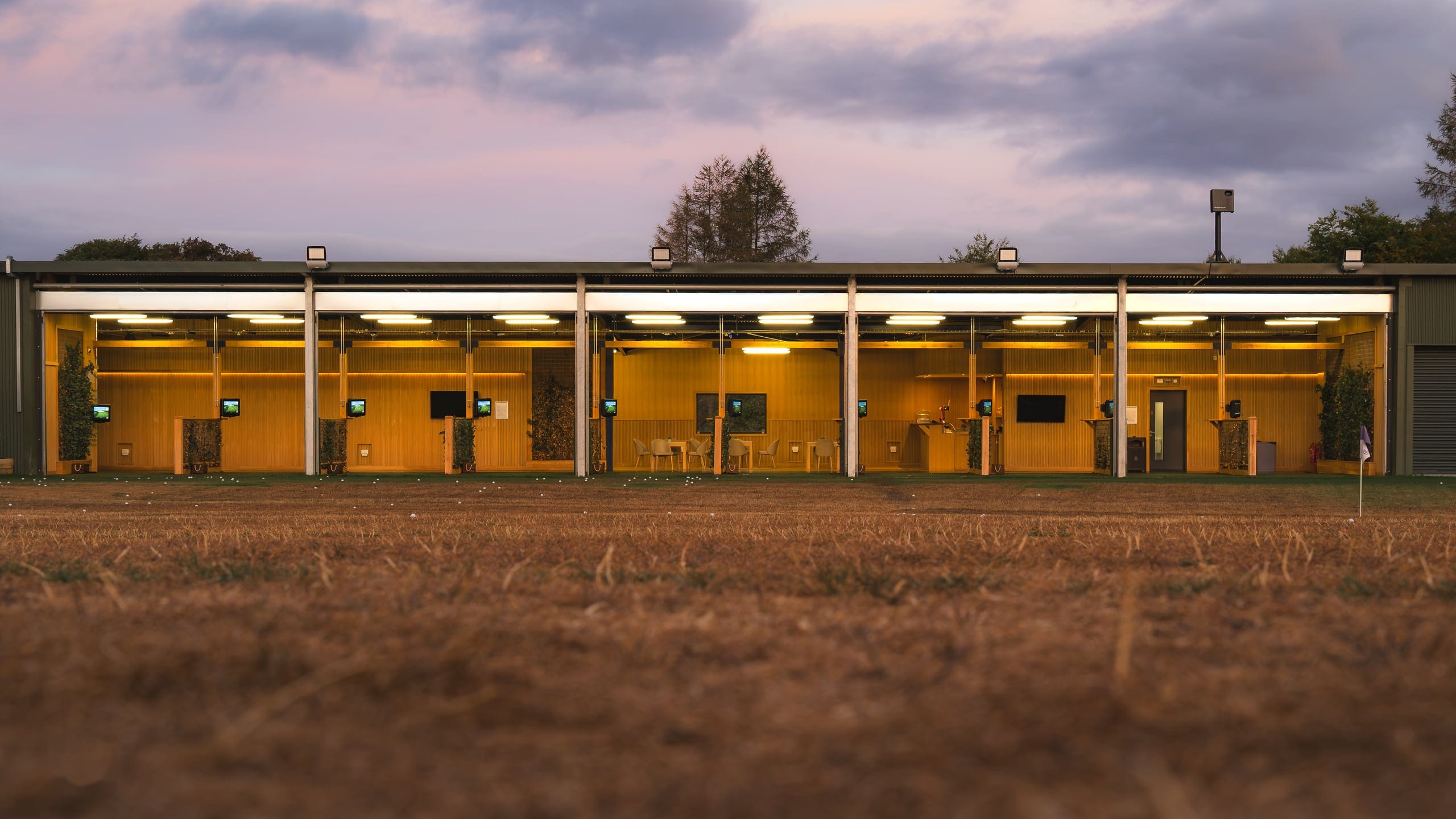 The driving range bays and clubhouse under a heavy sky at Basingstoke Golf Club