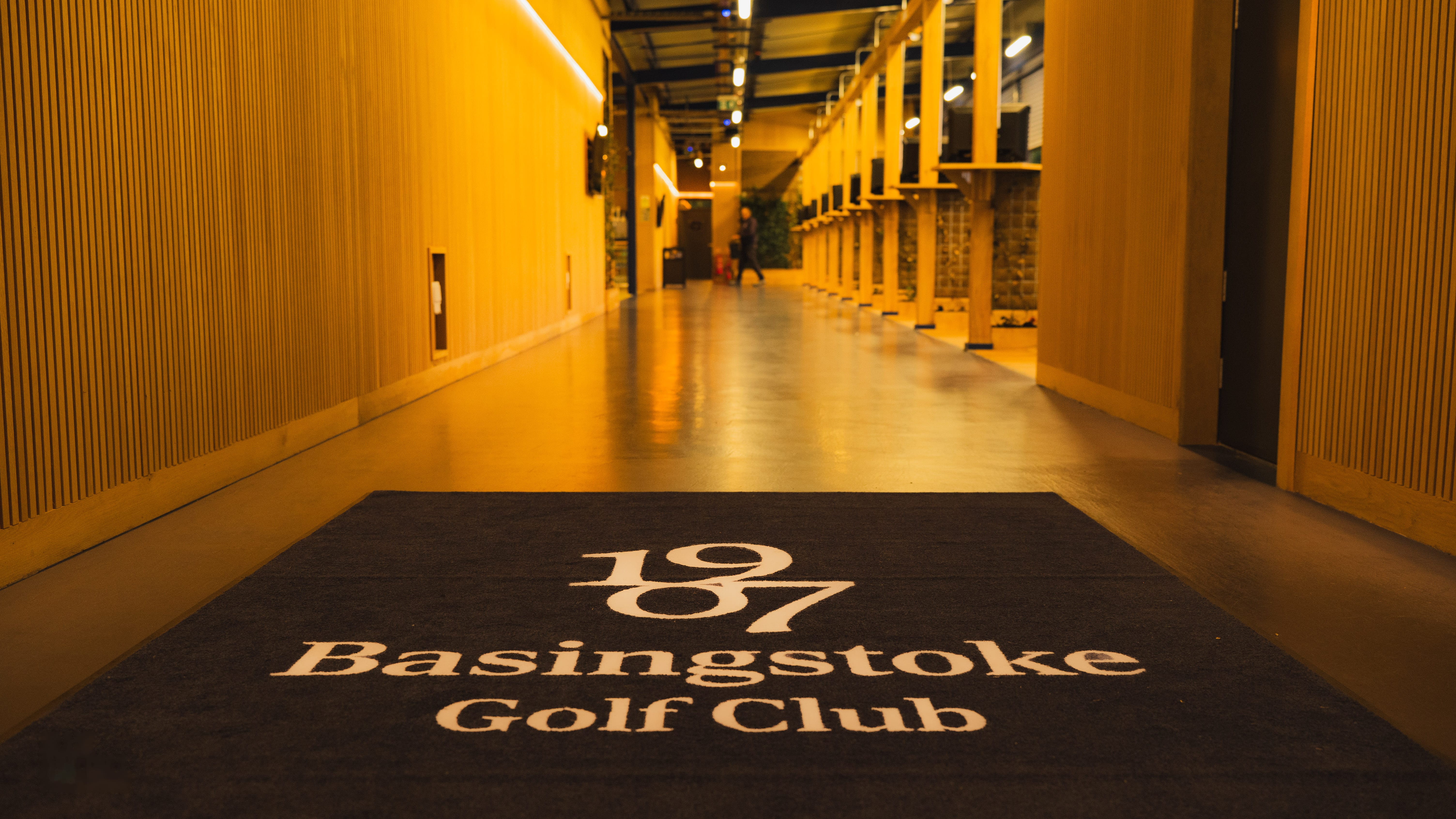 The "1907 Basingstoke Golf Club" branded mat inside the Academy entrance corridor