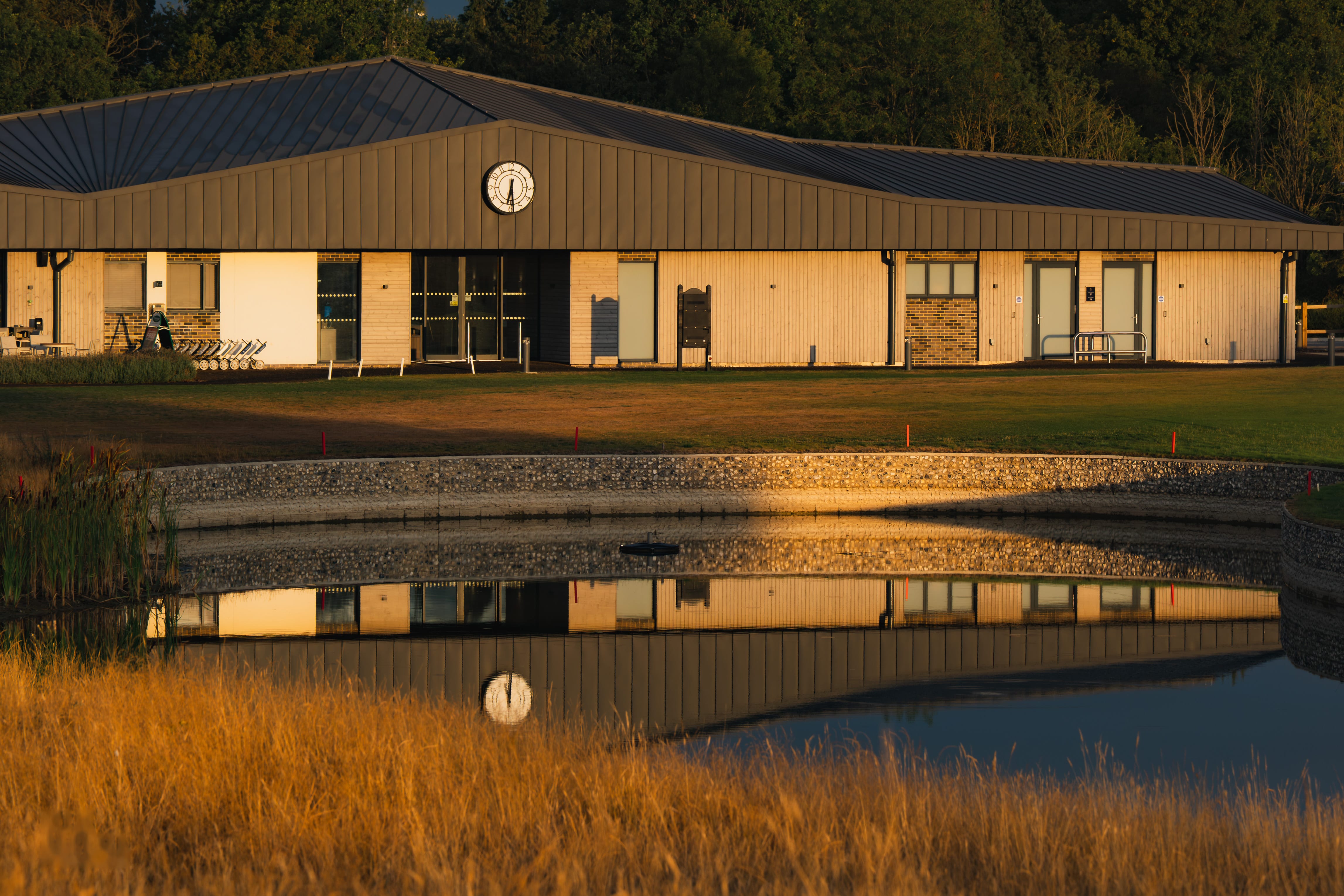 The clubhouse reflected across the pond at golden hour