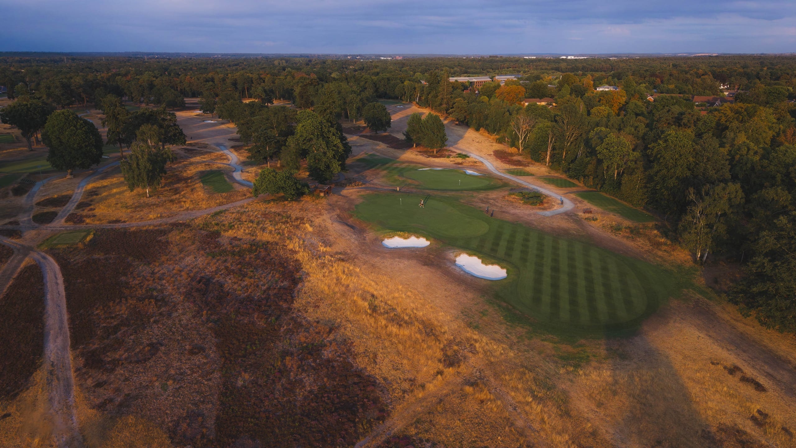 Aerial view of a green in autumn colour, golfers putting below