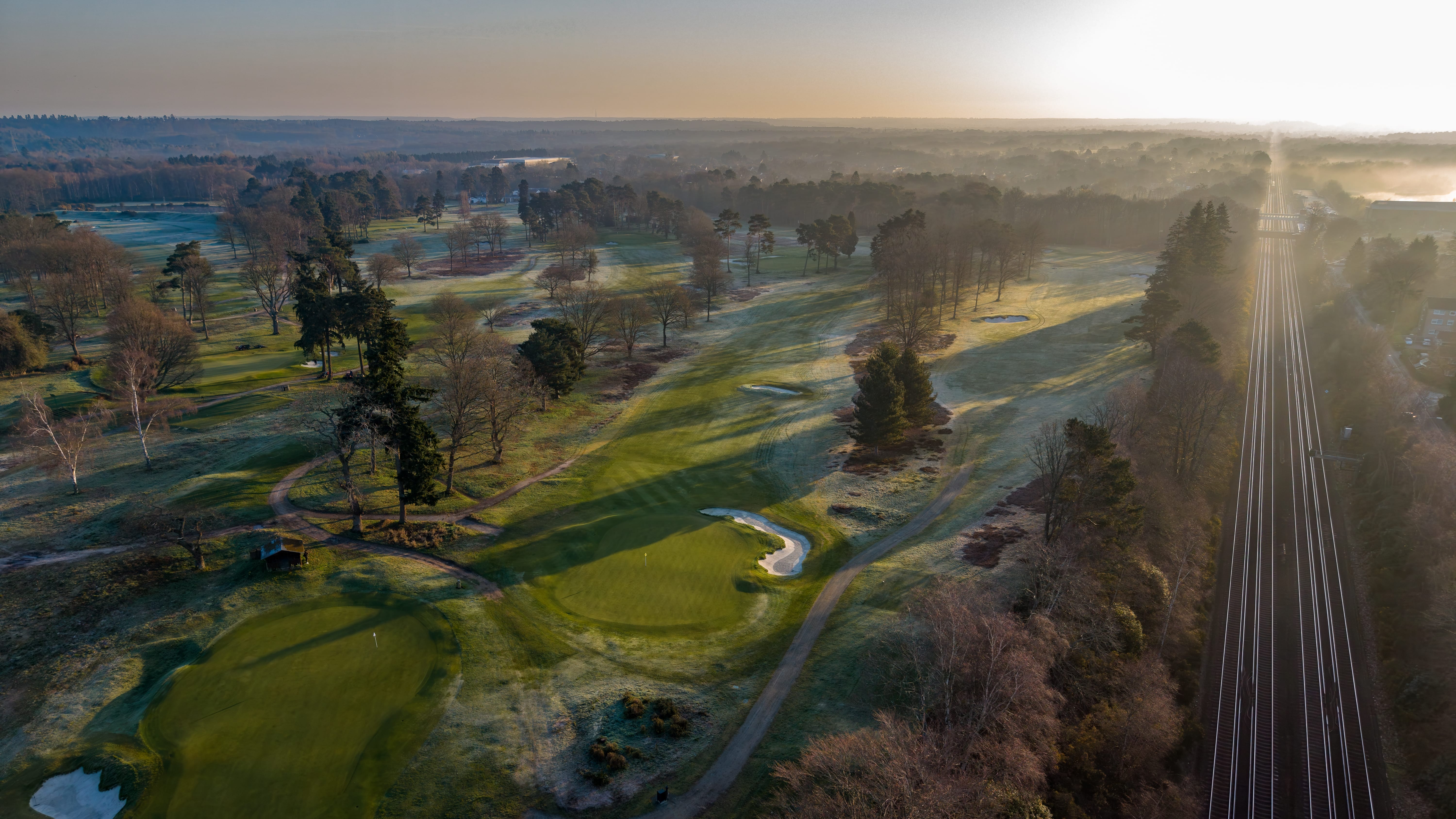 A frosted green and bunker at sunrise, the course still white with frost