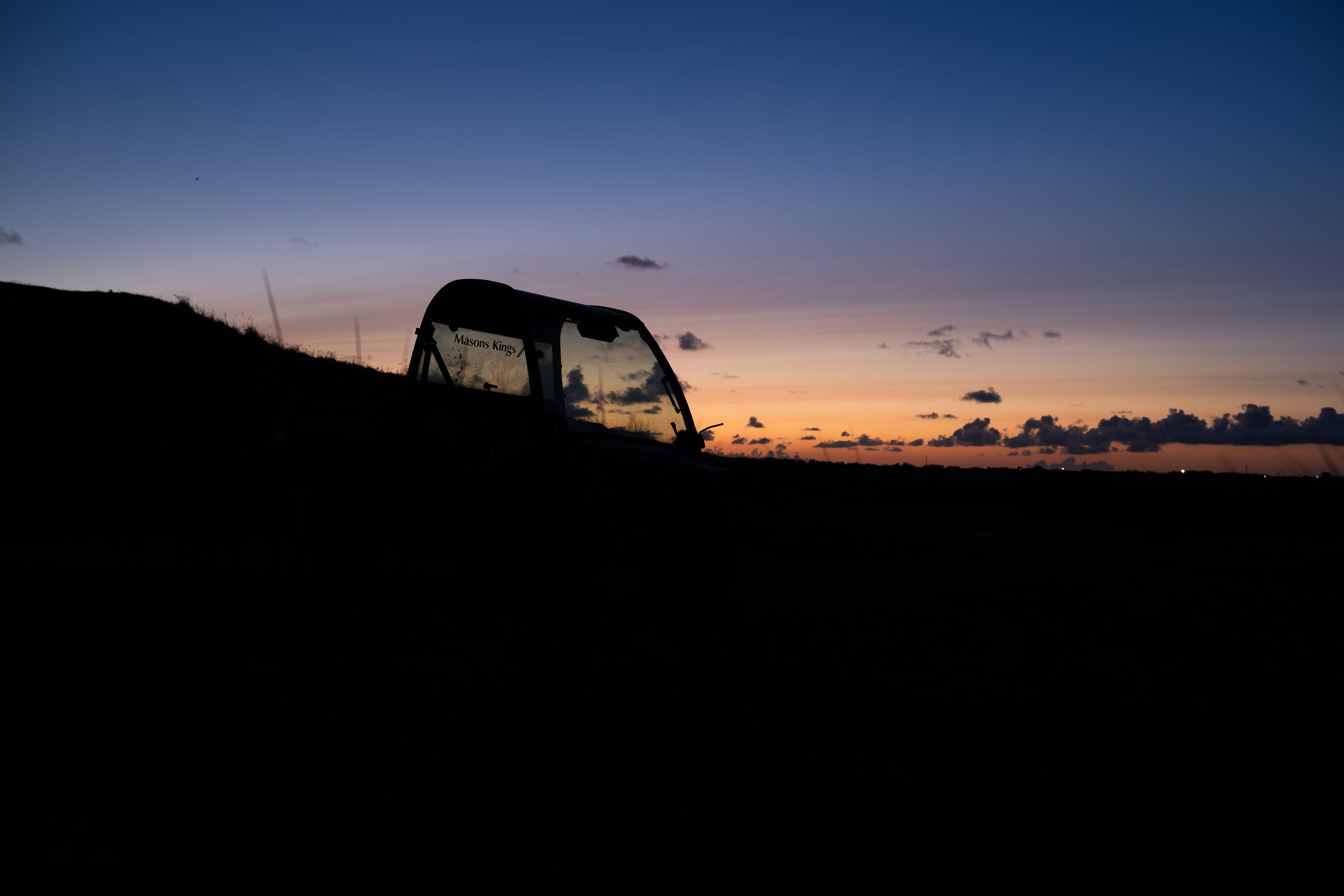 A greenkeeping buggy silhouetted against the sunset