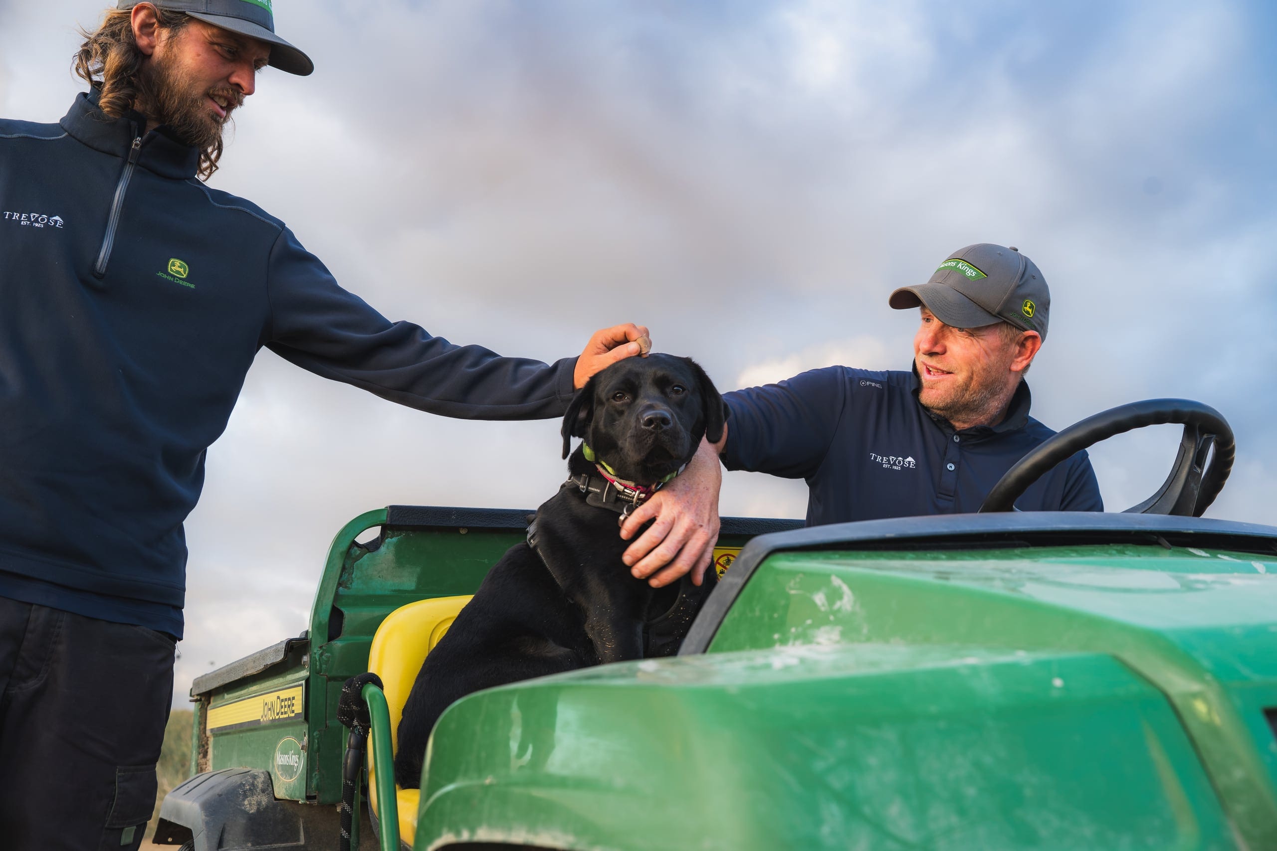 Two of the greenkeeping team, and the dog, up on the tractor at Trevose