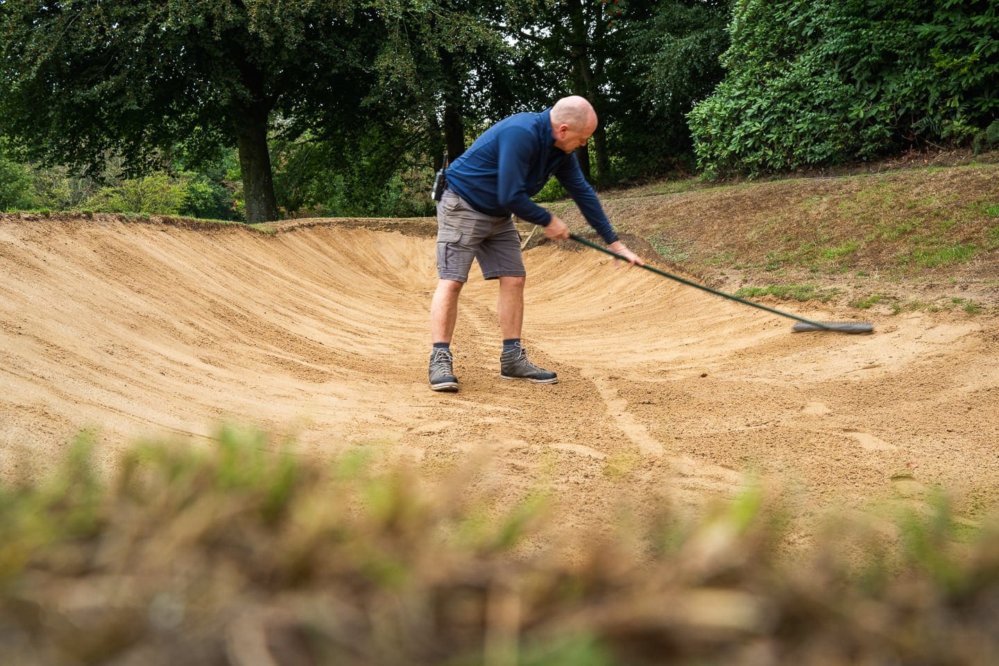 A greenkeeper raking a bunker