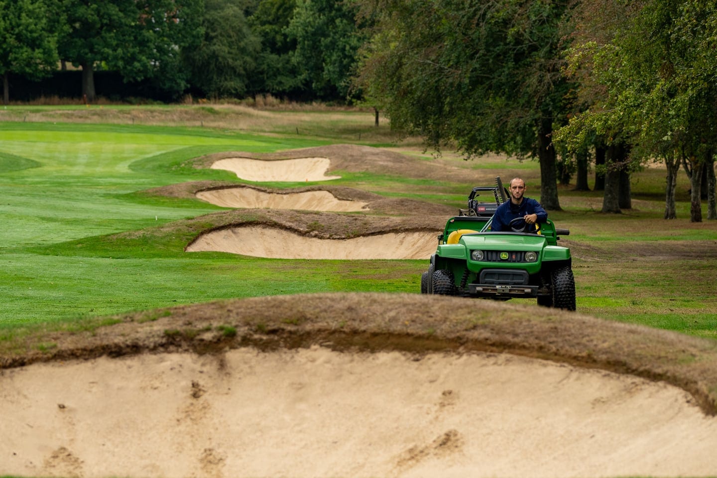 A utility vehicle parked beside a bunker in the parkland